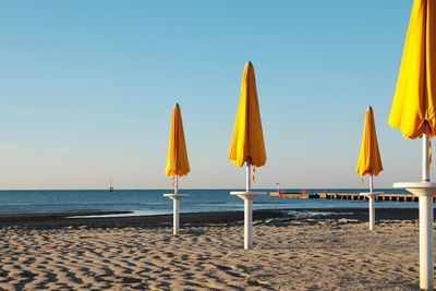 Parasols on beach against clear sky