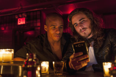 Young man using smart phone while sitting in laptop