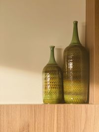 Close-up of empty bottles on table against wall at home