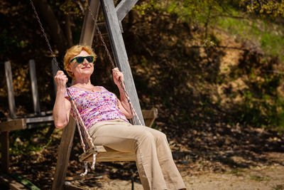 Senior woman joyfully swinging on a swing and having fan