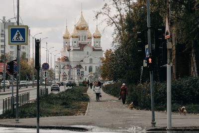 People walking on road amidst buildings in city