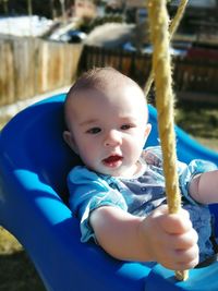 Close-up of cute baby girl sitting in swing at playground