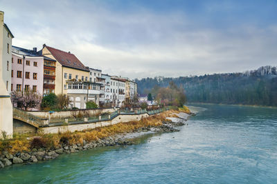 Buildings by river against sky in city