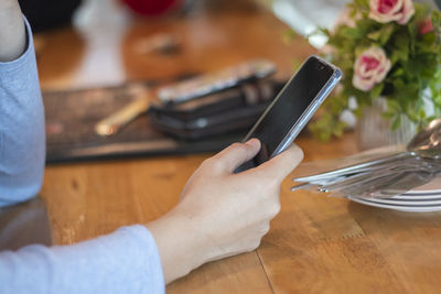 Midsection of woman holding smart phone on table