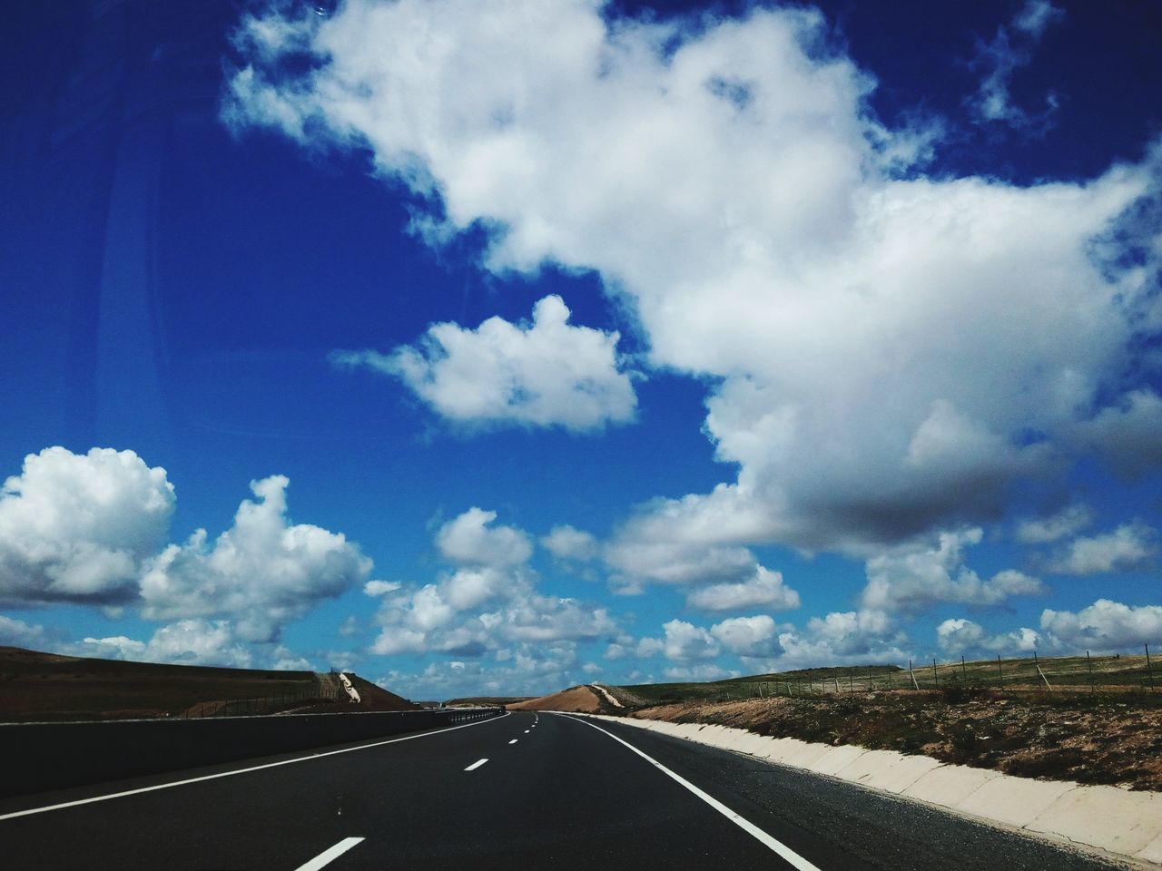 cloud - sky, sky, road, transportation, direction, the way forward, symbol, marking, no people, road marking, nature, day, sign, landscape, environment, empty road, tranquility, diminishing perspective, scenics - nature, beauty in nature, outdoors, dividing line, long, car point of view