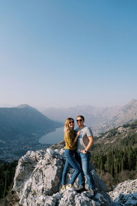 Rear view of woman sitting on mountain against clear sky