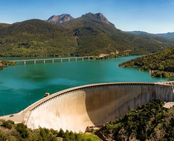 Scenic view of dam and mountains against sky