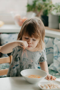 A little girl is sitting at the kitchen table eating soup. high quality photo