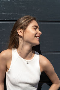 Happy young woman standing against wall