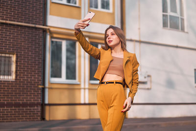 Young woman taking selfie on phone while standing in city