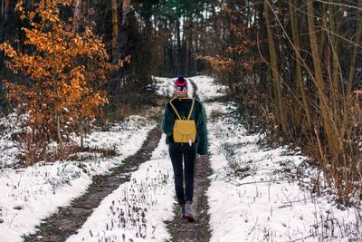 Portrait of young woman standing in snow covered forest