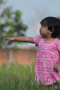 Cute girl with arms raised on field