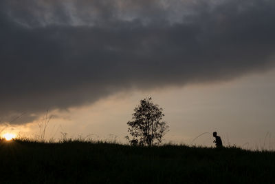 Silhouette man on field against sky during sunset