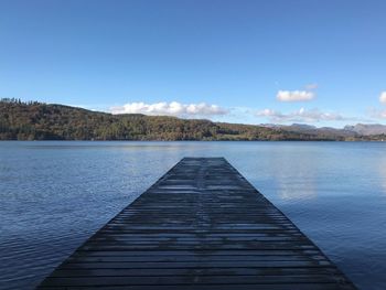 Pier over lake against blue sky