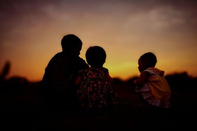 Siblings against sky during sunset