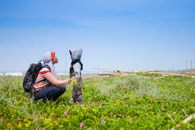 People sitting on field against sky