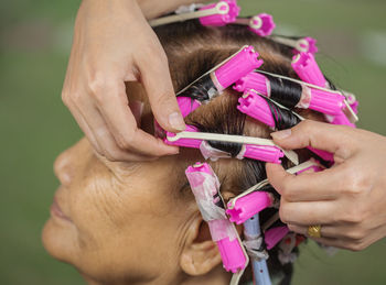 Stylist rolling woman hair at salon