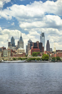 View of buildings at waterfront against cloudy sky