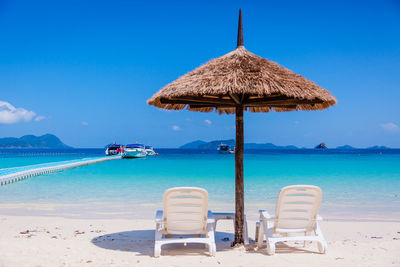 Chairs on beach against blue sky