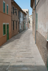 Empty alley amidst buildings in residential district on sunny day