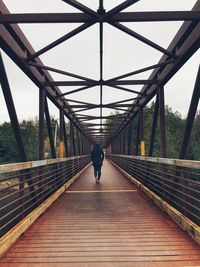 Rear view of woman walking on footbridge