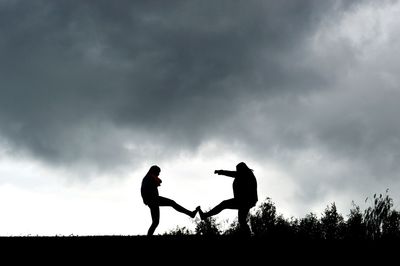 Silhouette people playing against sky