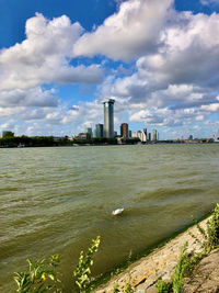 Buildings by river against sky in city