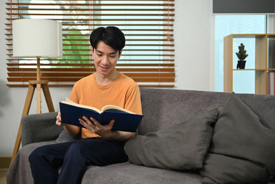 Young man using laptop while sitting on sofa at home