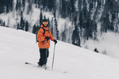 Skier wearing helmet and goggle standing on snow