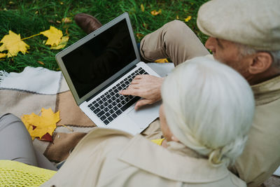 Rear view of couple video calling on laptop at park