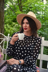 Young woman drinking coffee while sitting on tree