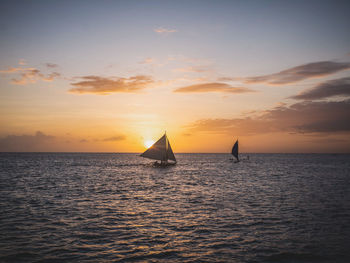 Sailboat sailing on sea against sky during sunset