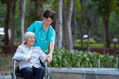 Nurse assisting patient sitting on wheelchair in park