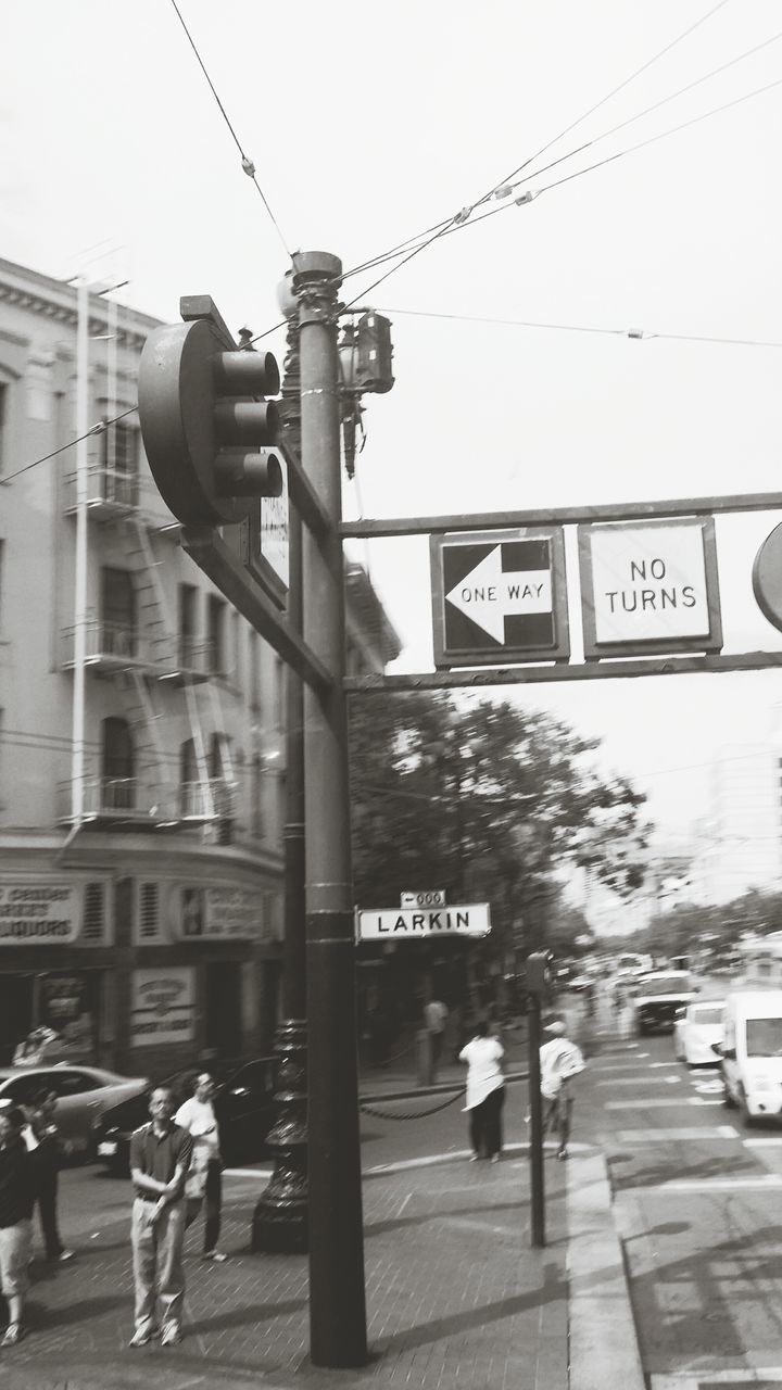 text, transportation, architecture, building exterior, built structure, communication, western script, street, city, men, information sign, walking, city life, sign, mode of transport, road sign, road, non-western script, power line