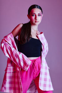 Portrait of young woman standing against wall