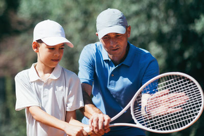 Coach teaching tennis to boy