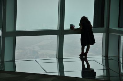 Side view of a girl standing against window