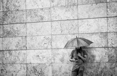 Man in rain against wall