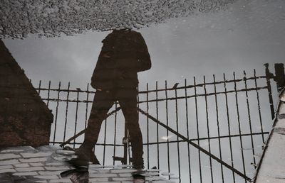 Man standing by railing against sea