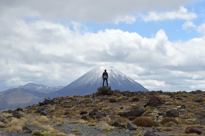 Man standing on cliff against snowcapped volcano