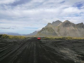 Vehicles on road against cloudy sky