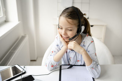 Portrait of cute girl sitting on table at home