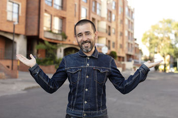 PORTRAIT OF SMILING MAN STANDING AGAINST CITY