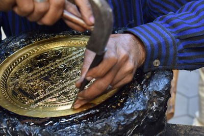 Midsection of man carving metal on rock