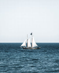 Sailboat sailing on sea against clear sky