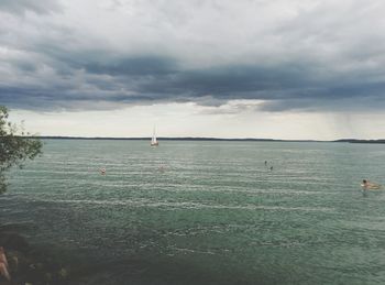 View of sailboat in sea against cloudy sky