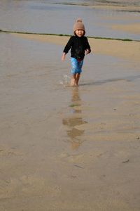 Boy standing on wet sand at beach