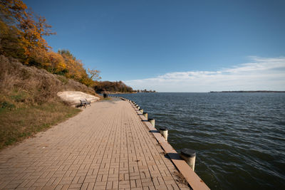 Footpath by sea against sky