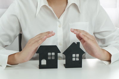 Midsection of man holding white house