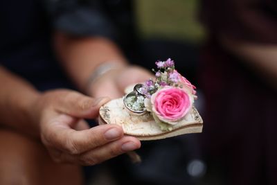 Midsection of woman holding wedding rings and flowers